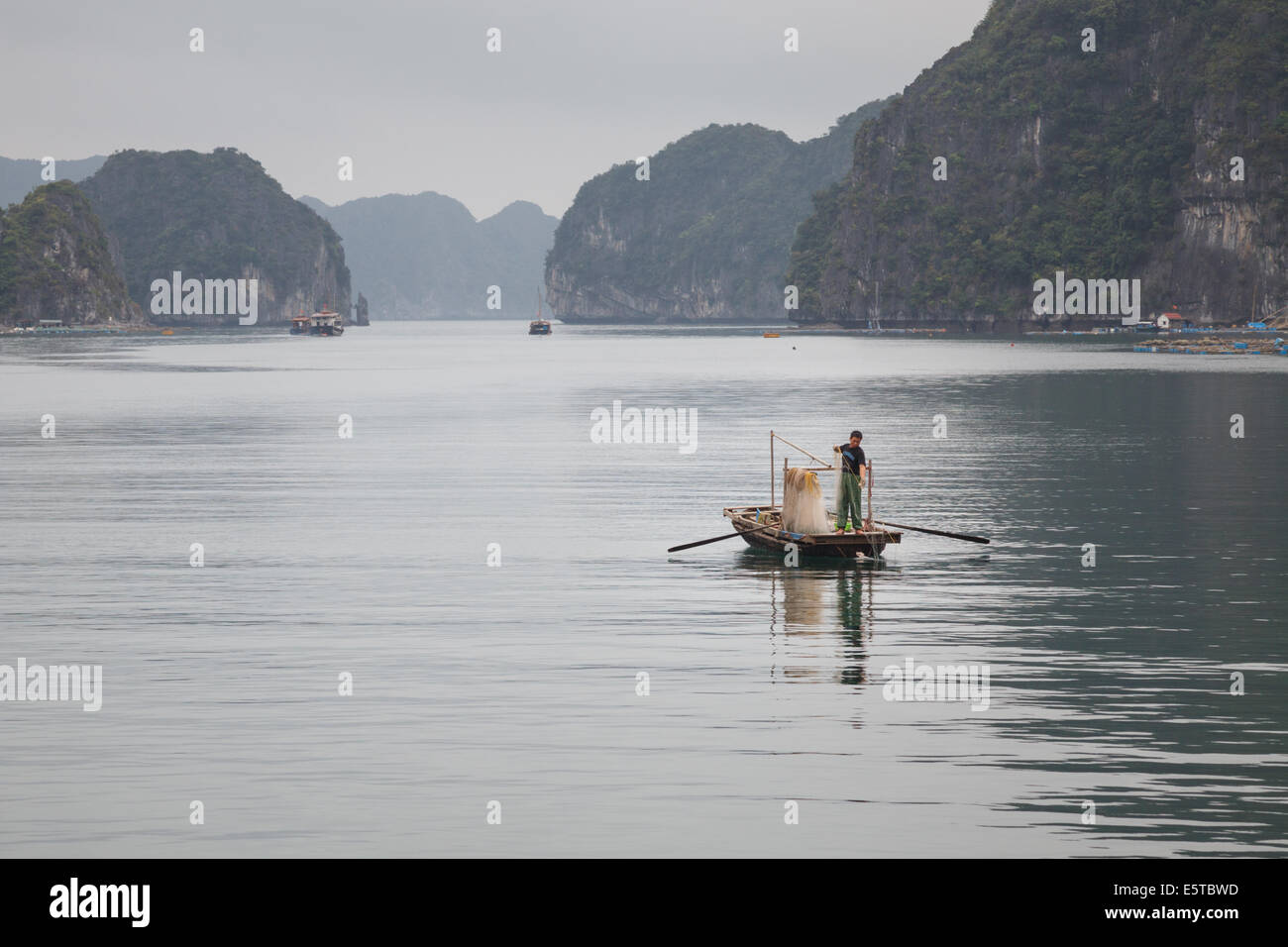 Ein Blick auf einen Mann Angeln in ihrer kleinen Holzboot in Lan-Ha-Bucht, in der Nähe von Cat Ba Island, Vietnam Stockfoto