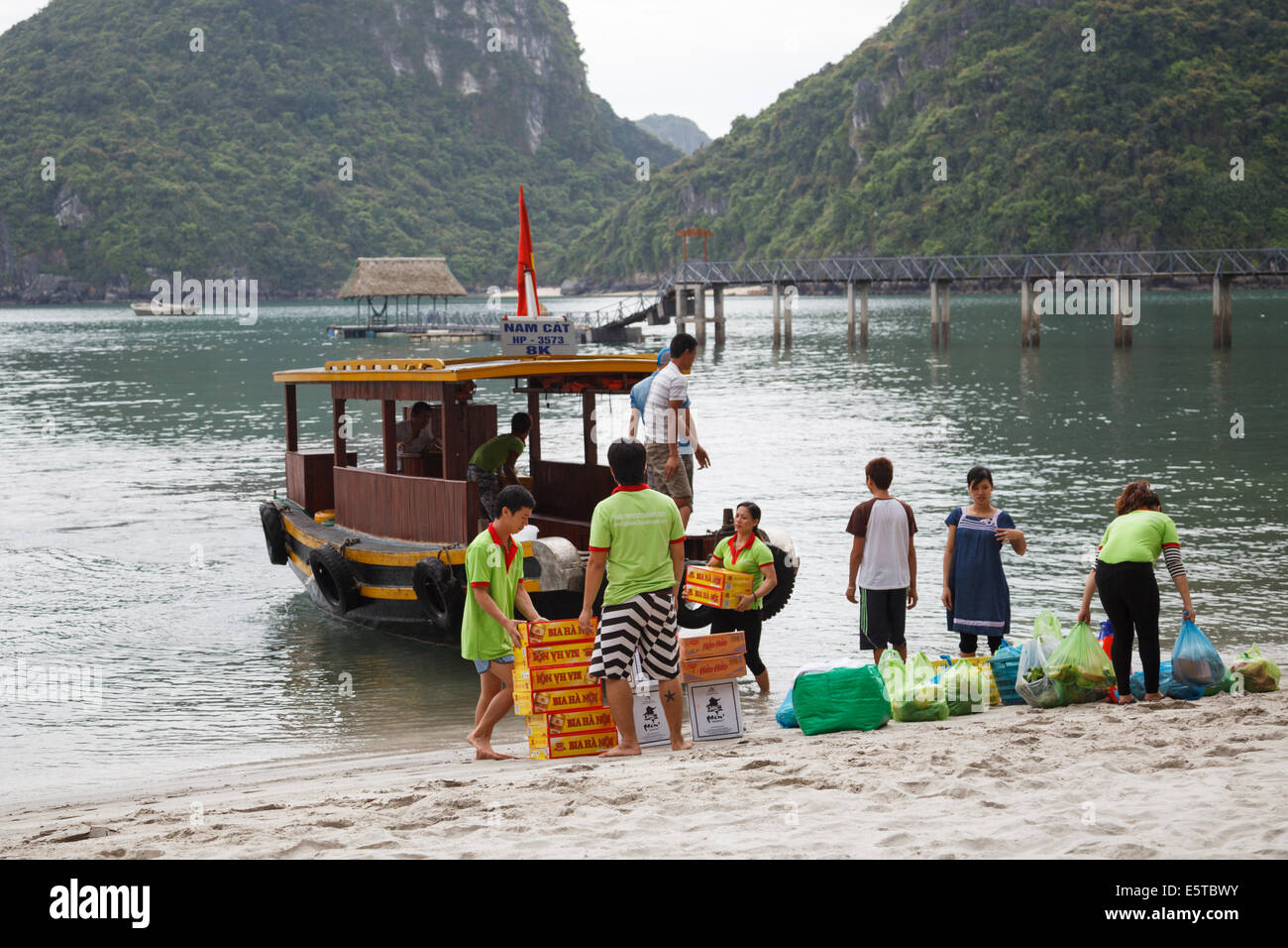 Mitarbeiter im Sandy Beach Resort, Cat Ba, auf Nam Cat Island in Lan-Ha-Bucht entladen tägliche Lieferungen, die mit dem Boot anreisen. Stockfoto