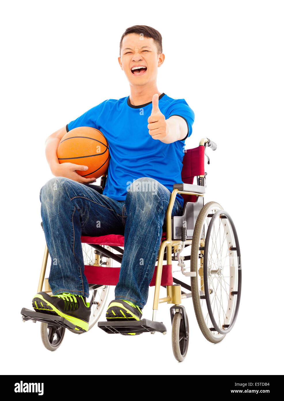hoffnungsvoller junger Mann sitzt auf einem Rollstuhl mit einem Basketball und Daumen hoch Stockfoto