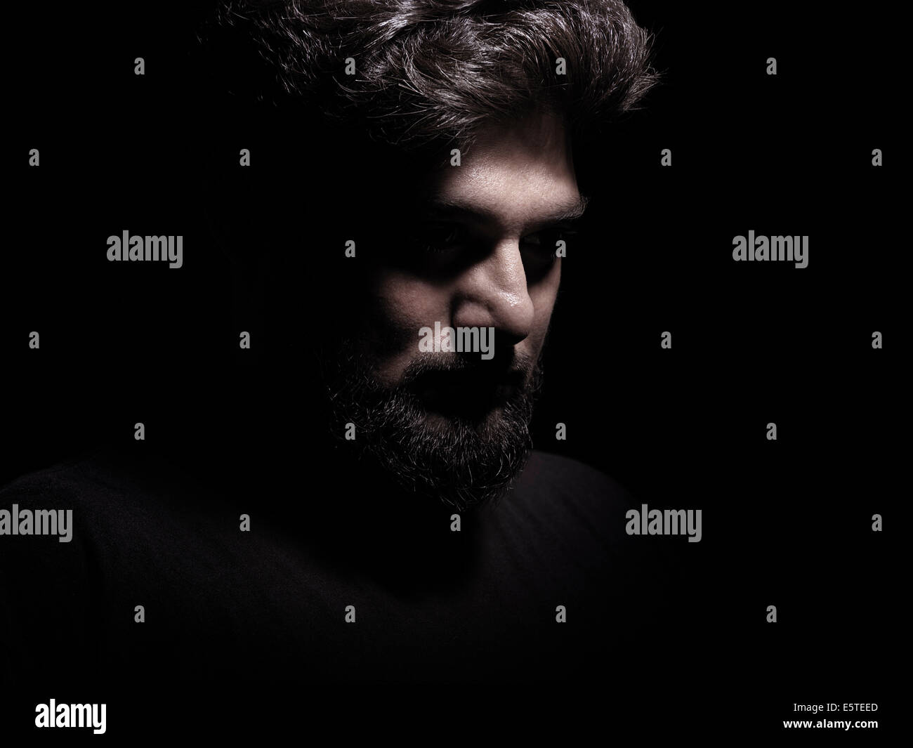 Lizenz erhältlich unter MaximImages.com - dramatisches schattenhaftes Porträt eines nachdenklichen Mannes isoliert auf schwarzem Hintergrund Stockfoto