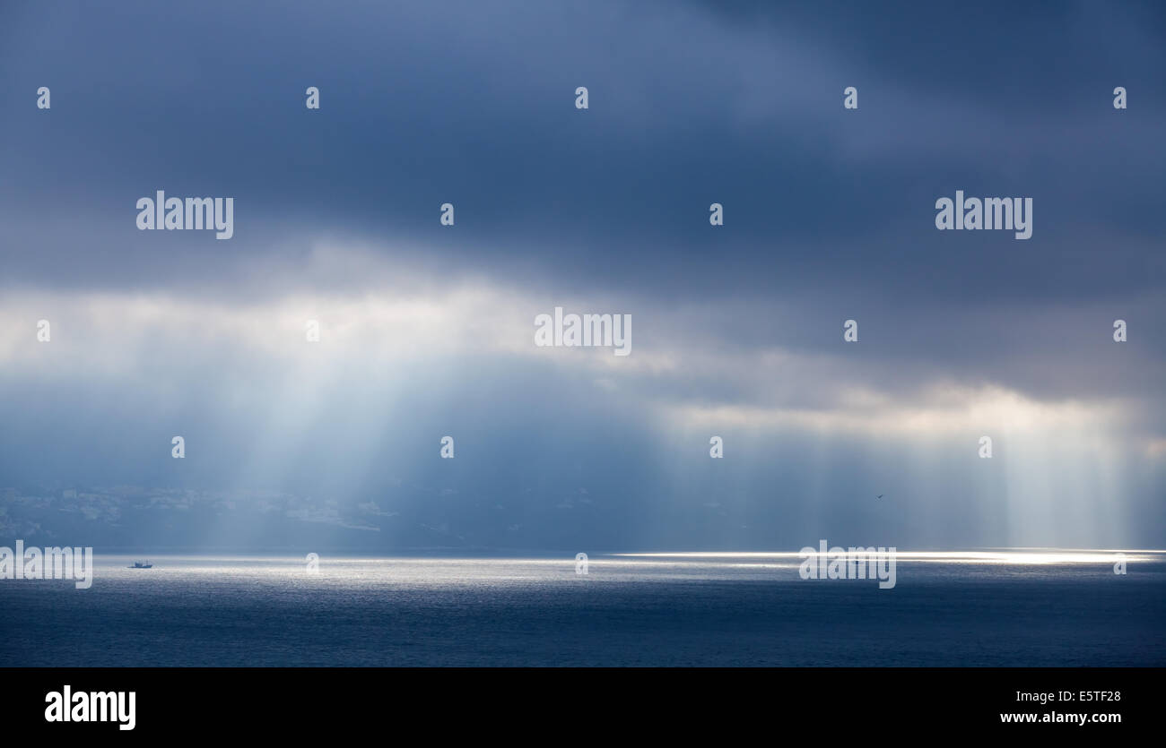 Sonnenlicht geht durch dunkle Wolken. Bucht von Tanger, Marokko Stockfoto