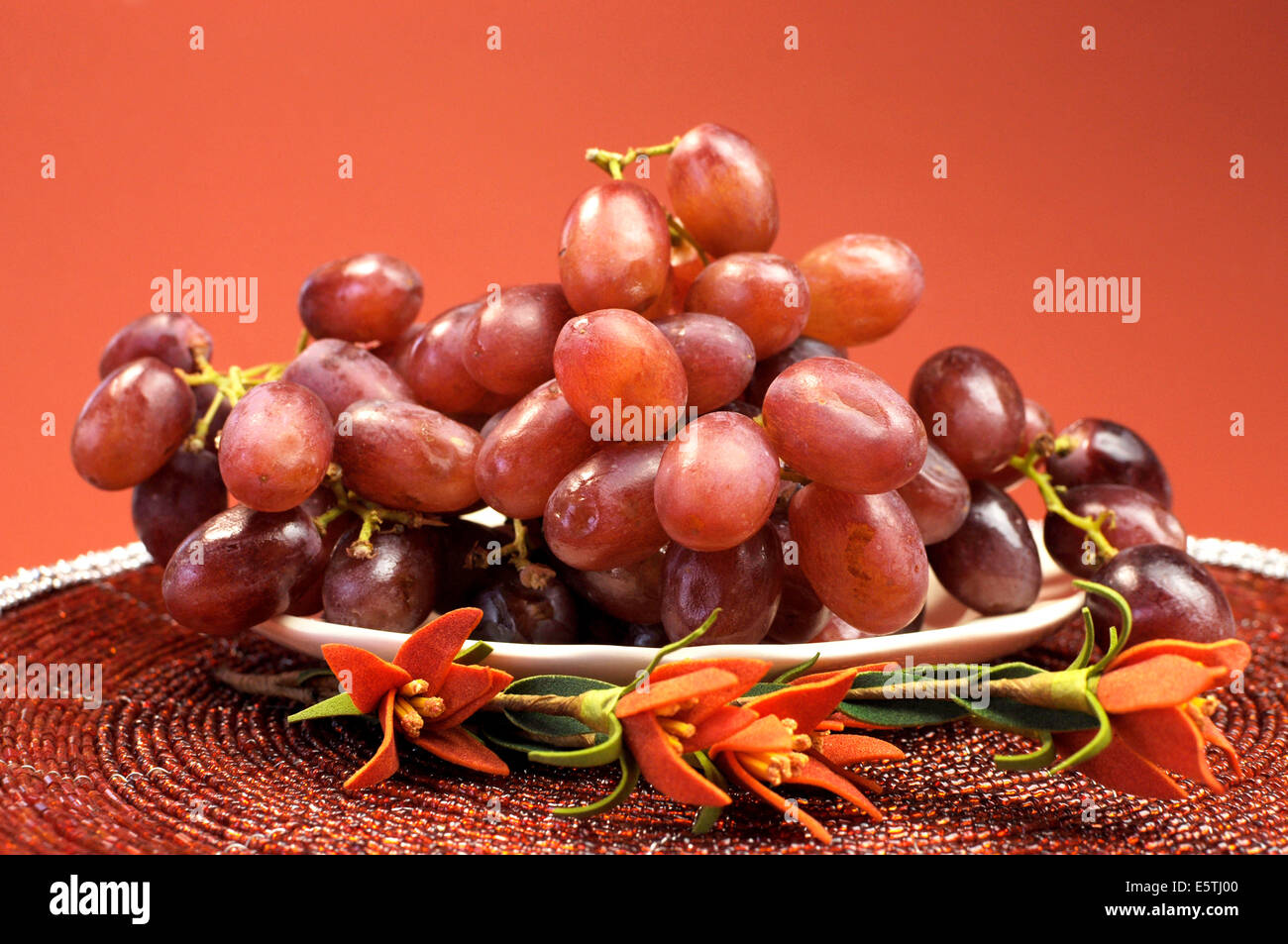 Teller mit gesunden Frucht, rote Trauben in rot braun Herbst fallen Einstellung mit Blumen. Stockfoto