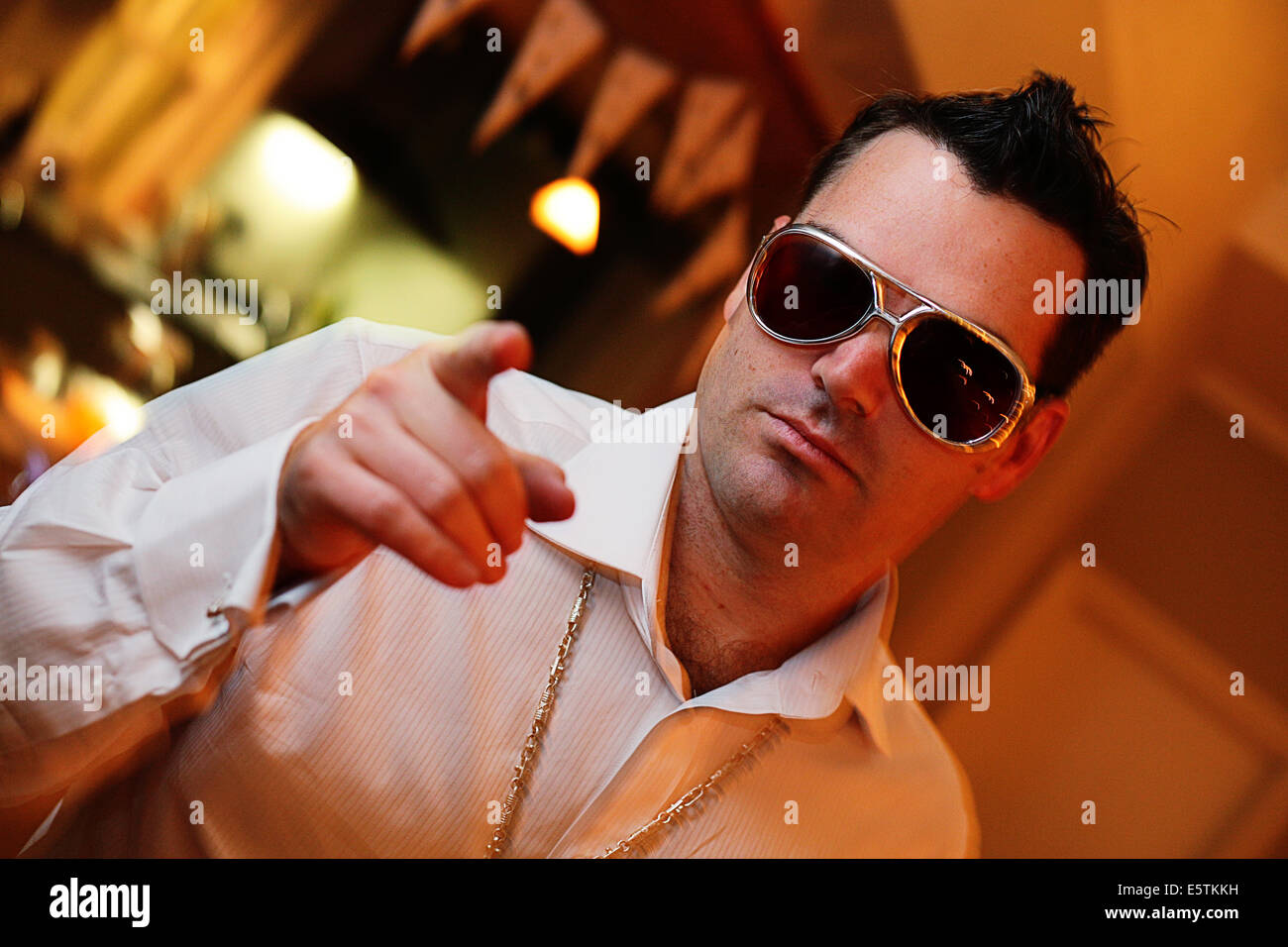 Eine dreißig acht Jahre alte Partei-Goer trägt eine Sonnenbrille und eine gefälschte Goldkette Stockfoto