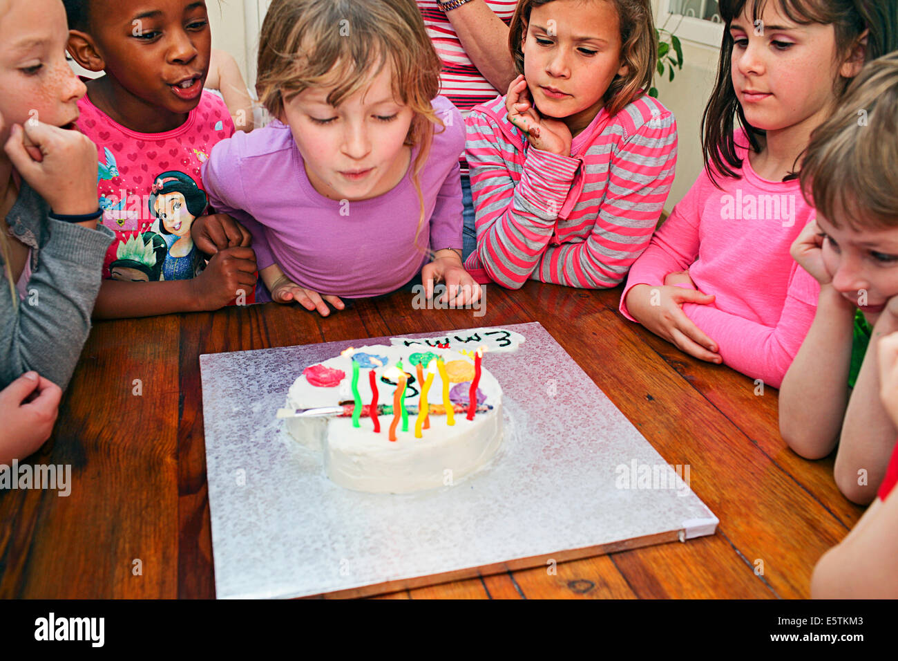 ziemlich 8-jährige Ausblasen der Kerzen auf ihrem Geburtstagskuchen Stockfoto