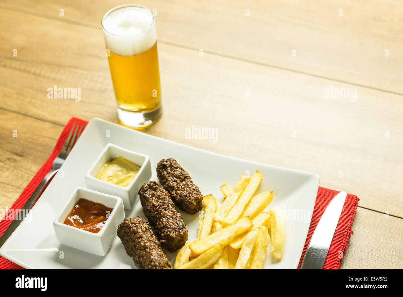 Traditionellen rumänischen Mici und Pommes Frites mit Ketchup, Senf und Bierglas Stockfoto