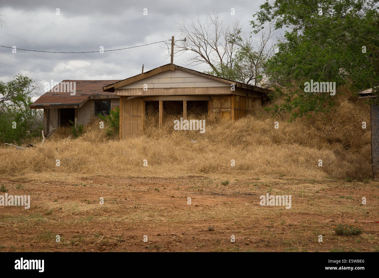Ein verlassenes Haus in einer kleinen ländlichen New Mexiko-Stadt ist in Tumbleweed und leiden frühen Stadien des Verfalls begraben. Stockfoto