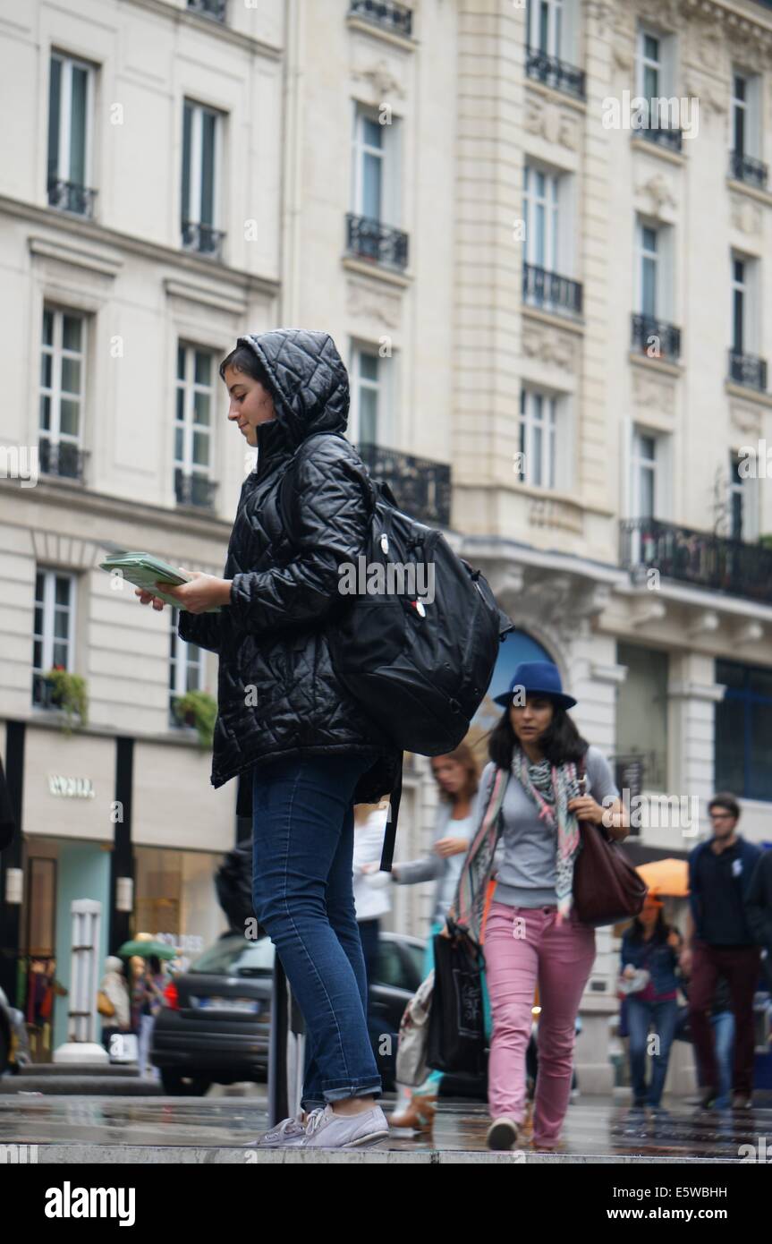 Eine junge weibliche Studentin verteilen von Flyern in einer Paris Straße im Regen Stockfoto