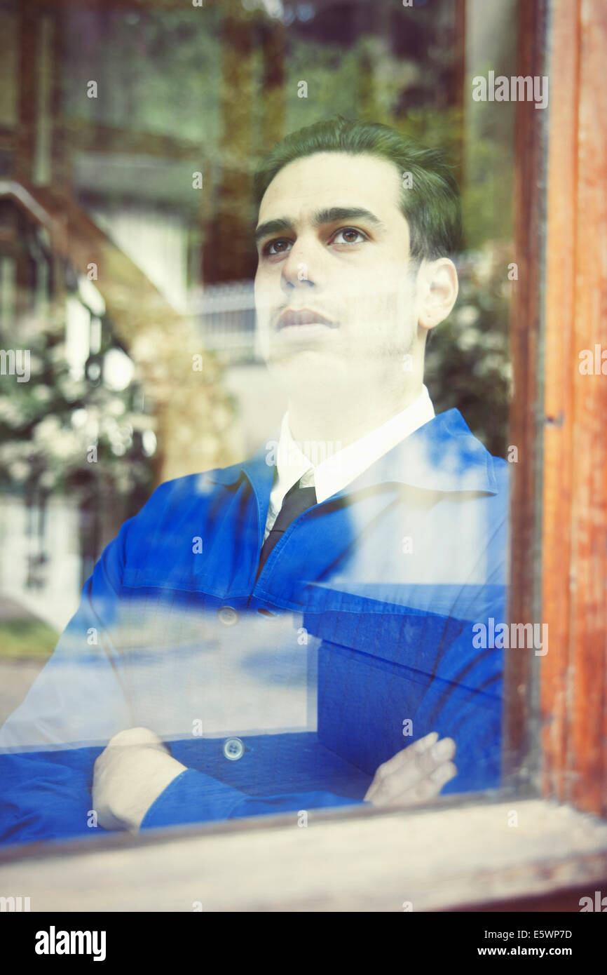 Porträt des jungen Mannes in Vintage Jacke Blick durch Fenster Stockfoto
