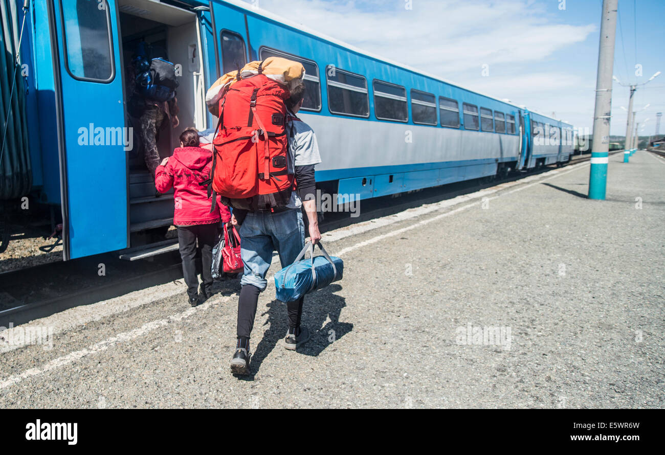Rückansicht des jungen Wanderer mit Rucksäcken einsteigen in einen Zug Stockfoto