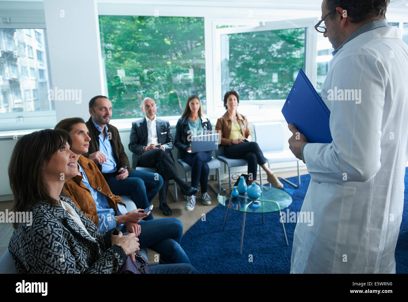 Gruppe von Menschen sitzen, mit Blick auf den Mann im Laborkittel Stockfoto