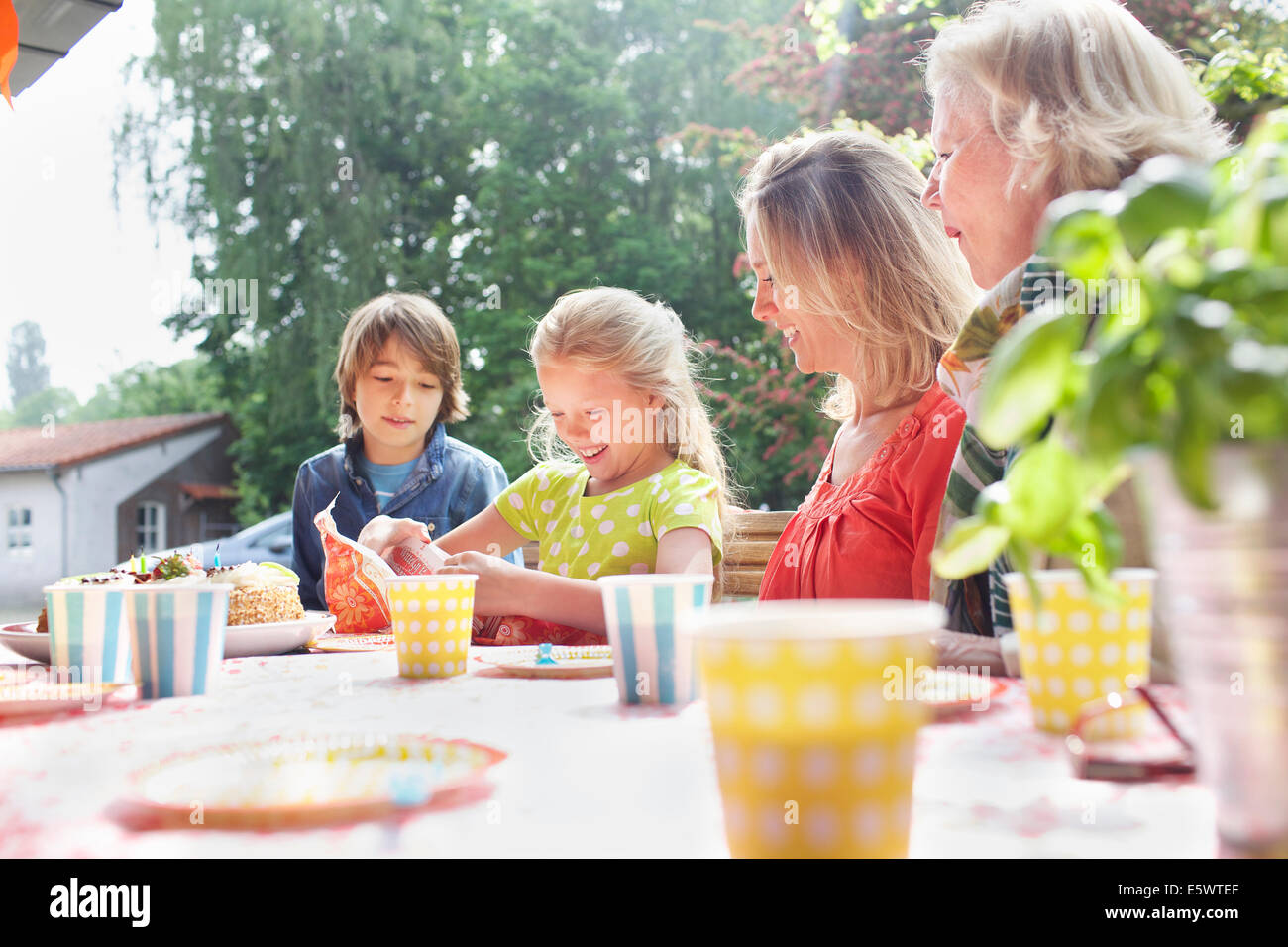 Mädchen mit ihrer Familie auf Geburtstagsparty Geburtstagsgeschenk öffnen Stockfoto