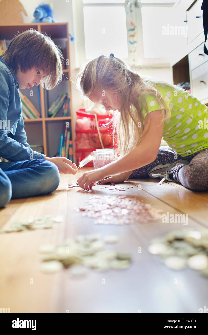 Bruder und Schwester counting-Münzen aus Einsparungen Glas Stockfoto