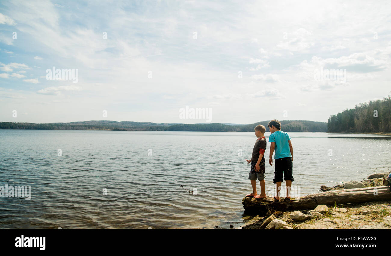 Zwei jungen stehen auf gefallenen Baum schaut in See Stockfoto