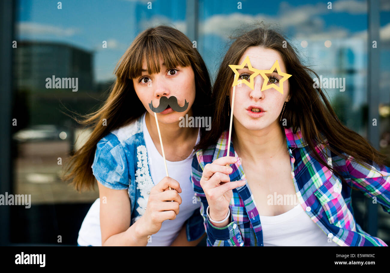 Porträt zweier junger Frauen, Schnurrbart und Brille Kostüm Masken hochhalten Stockfoto