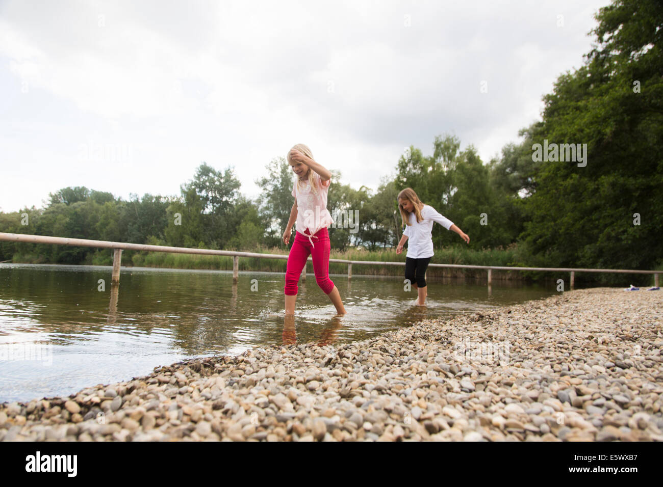 Zwei Mädchen im ländlichen See paddeln Stockfoto