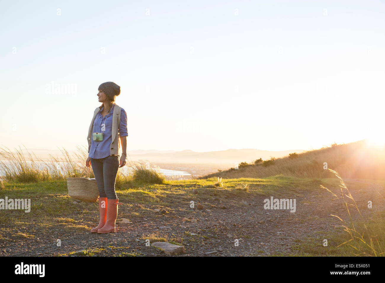 Junge Frau, die auf Hügel bei Sonnenuntergang Stockfoto