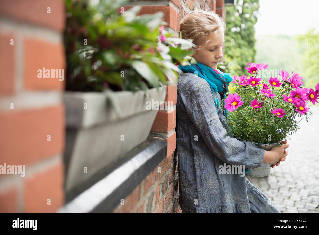 Porträt eines Mädchens mit Blume Topfpflanze im Garten Wand gelehnt Stockfoto