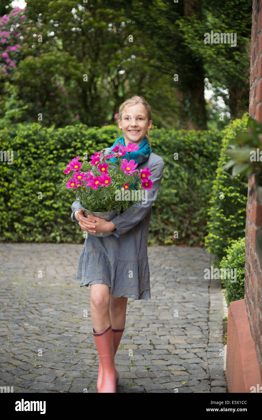 Porträt von Mädchen mit Blume Topfpflanze im Garten Stockfoto
