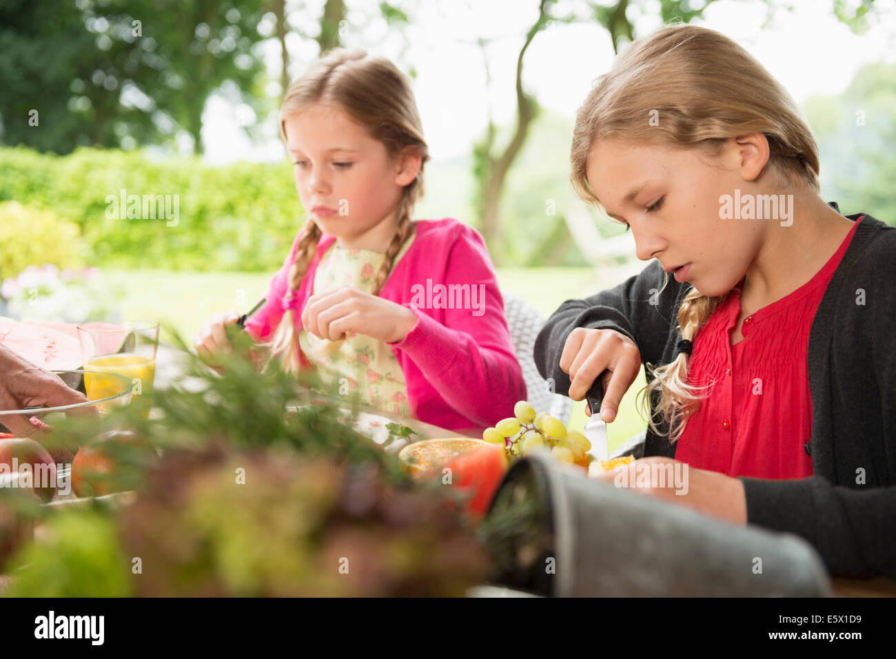 Zwei Schwestern bei Terrassentisch frisches Obst schneiden Stockfoto