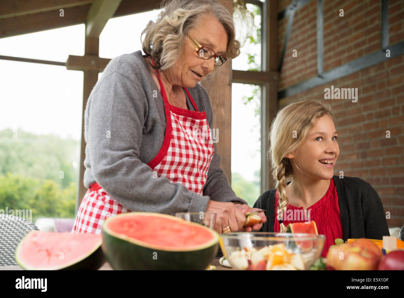 Mädchen und Großmutter Küche Tisch lernt, Scheibe frisches Obst Stockfoto
