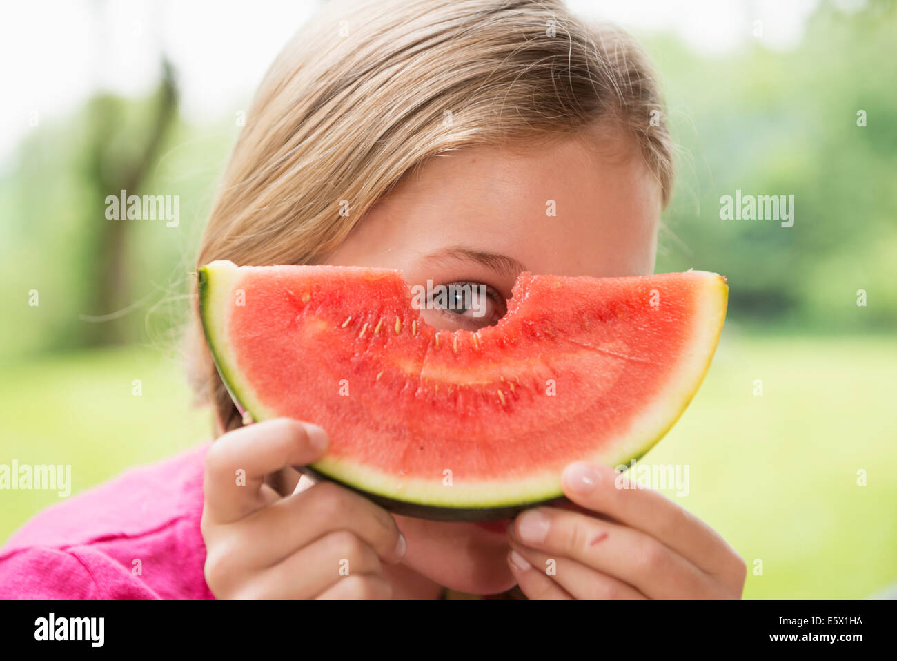 Porträt eines Mädchens spähte durch Wassermelone Slice hautnah Stockfoto