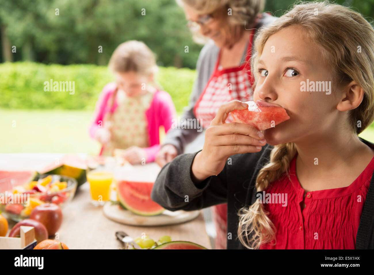 Schelmischen Mädchen am Terrassentisch Essen Wassermelone Stück Stockfoto
