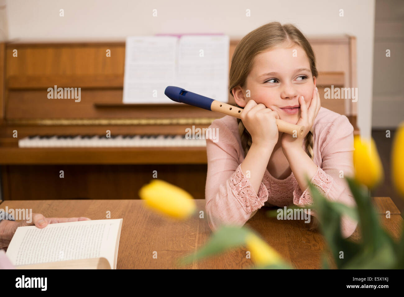 Gelangweilt abgelenkt Mädchen mit Recorder Instrument im Speisesaal Stockfoto