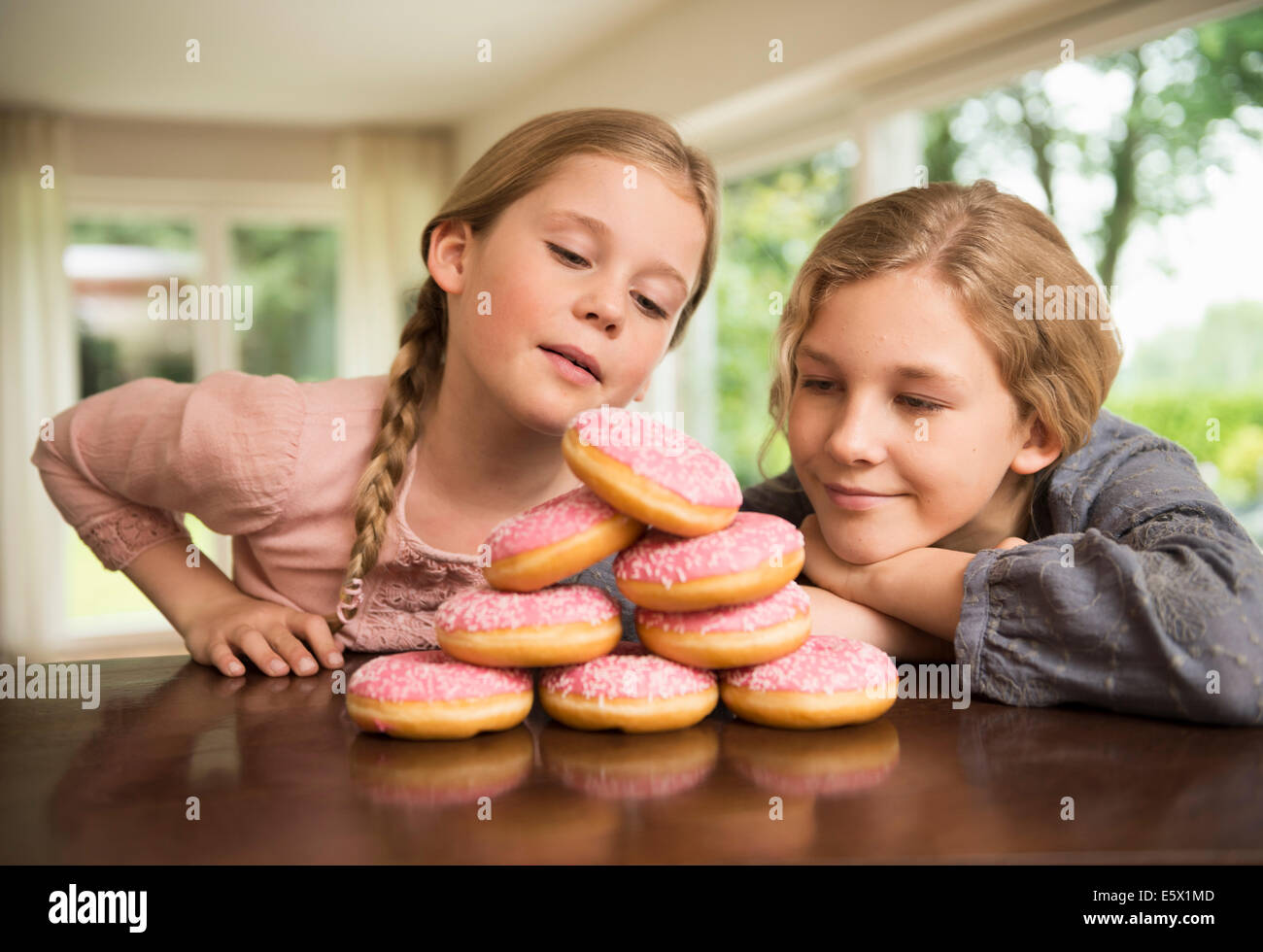 Zwei Schwestern Blick auf Stapel mit Donut Löcher auf Küchentisch Stockfoto