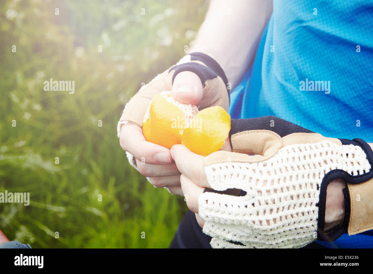 Radfahrer peeling Orange mit behandschuhten Händen Stockfoto