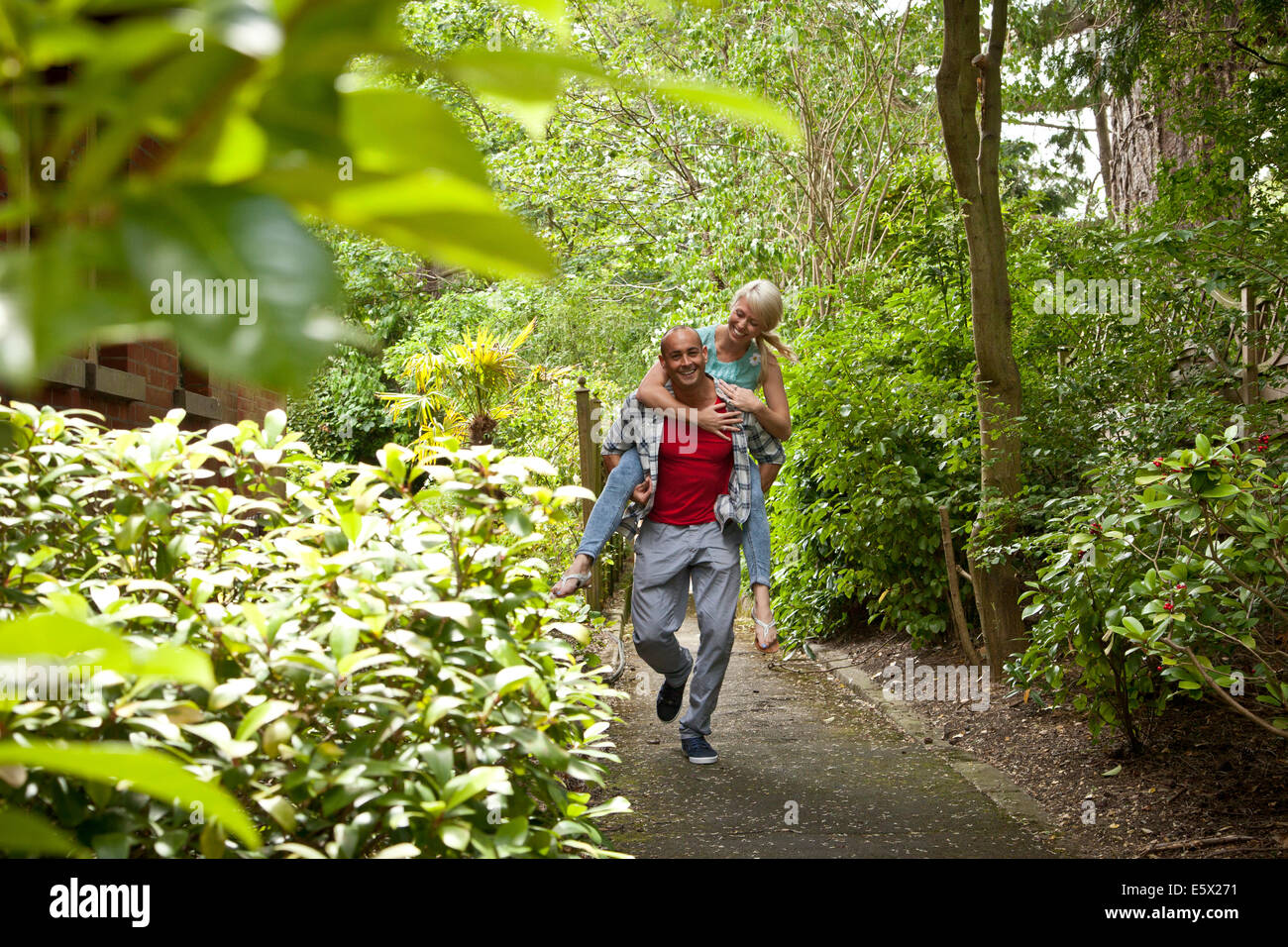 Glückliche Paare, die Spaß mit Huckepack im Garten Stockfoto