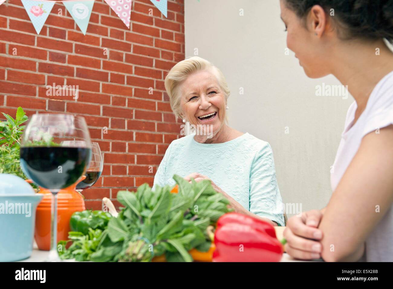 Zwei Frauen im Chat während der Zubereitung von Speisen am Gartentisch Stockfoto