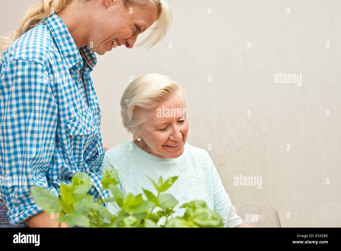 Ältere Frau und Enkelin im Chat am Gartentisch Stockfoto