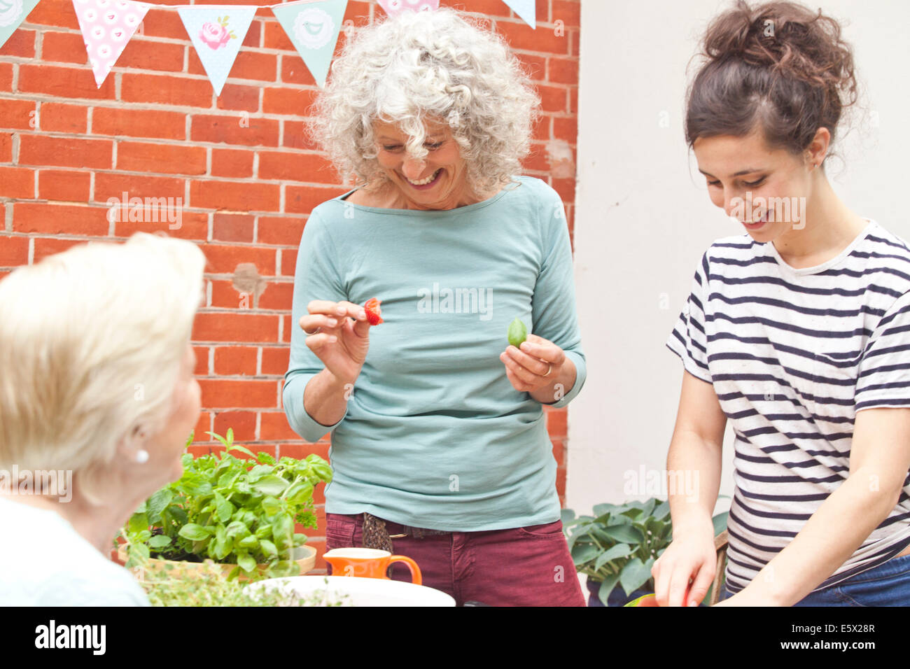 Drei Frauen, die Zubereitung von frischen Speisen am Gartentisch Stockfoto