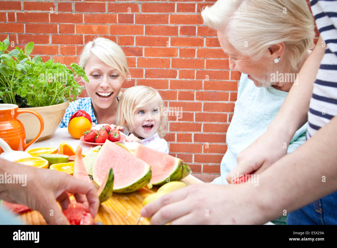 Vier Frauen und einem weiblichen Kleinkind, die Zubereitung von Speisen am Gartentisch Stockfoto