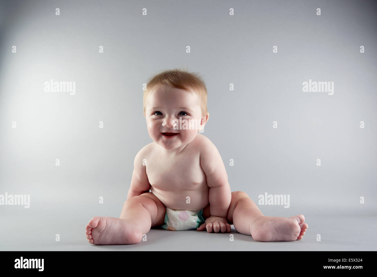 Studioportrait von lächelndes Babymädchen sitzend Stockfoto