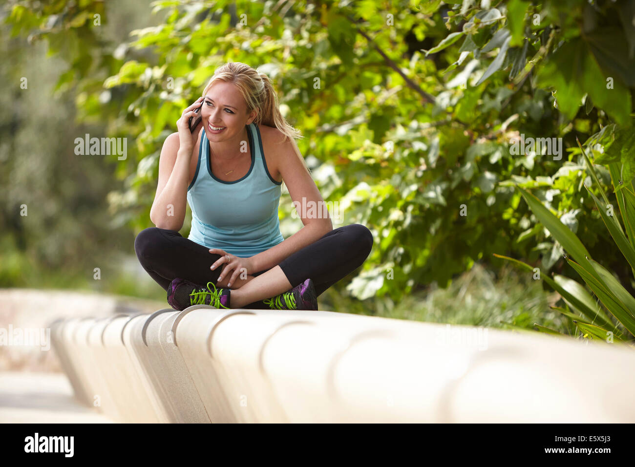 Frau im Chat auf Smartphone auf steinerne Sitzgelegenheiten Stockfoto