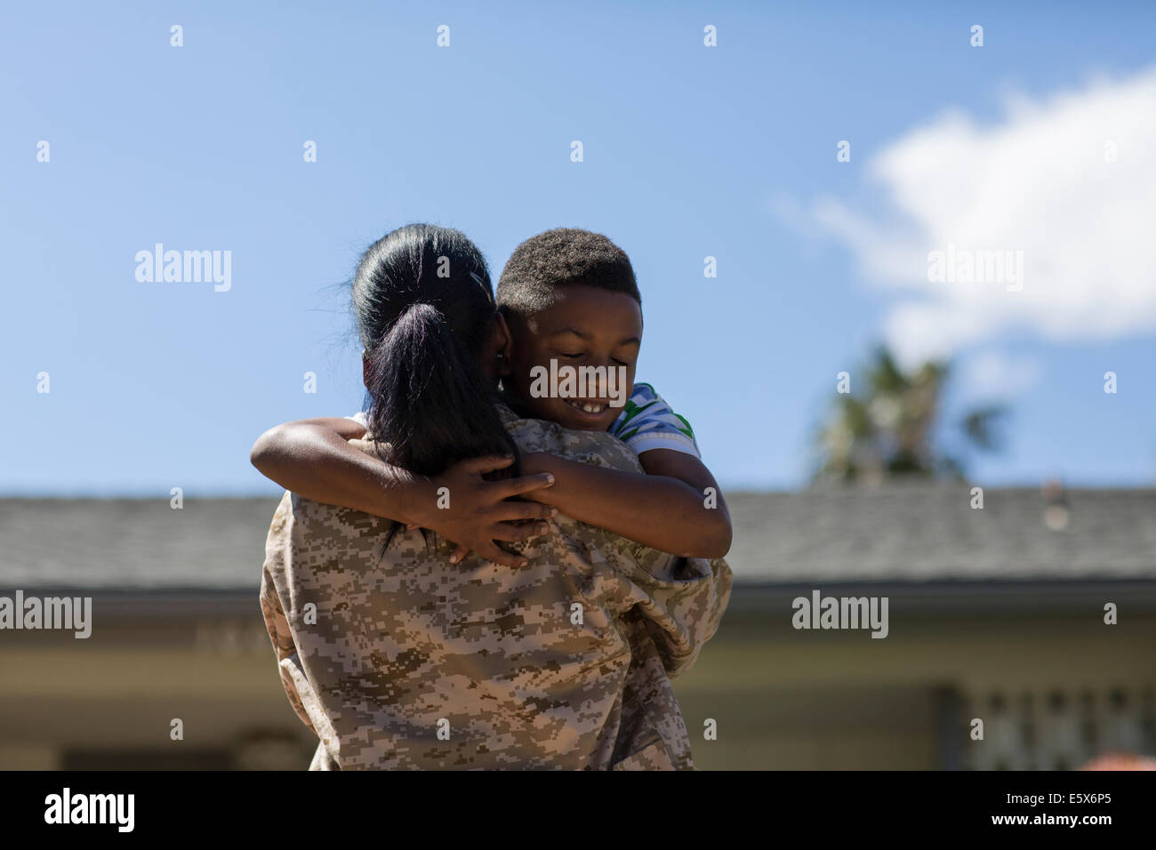 Rückansicht der Soldatin umarmt Sohn auf Heimkehr Stockfoto
