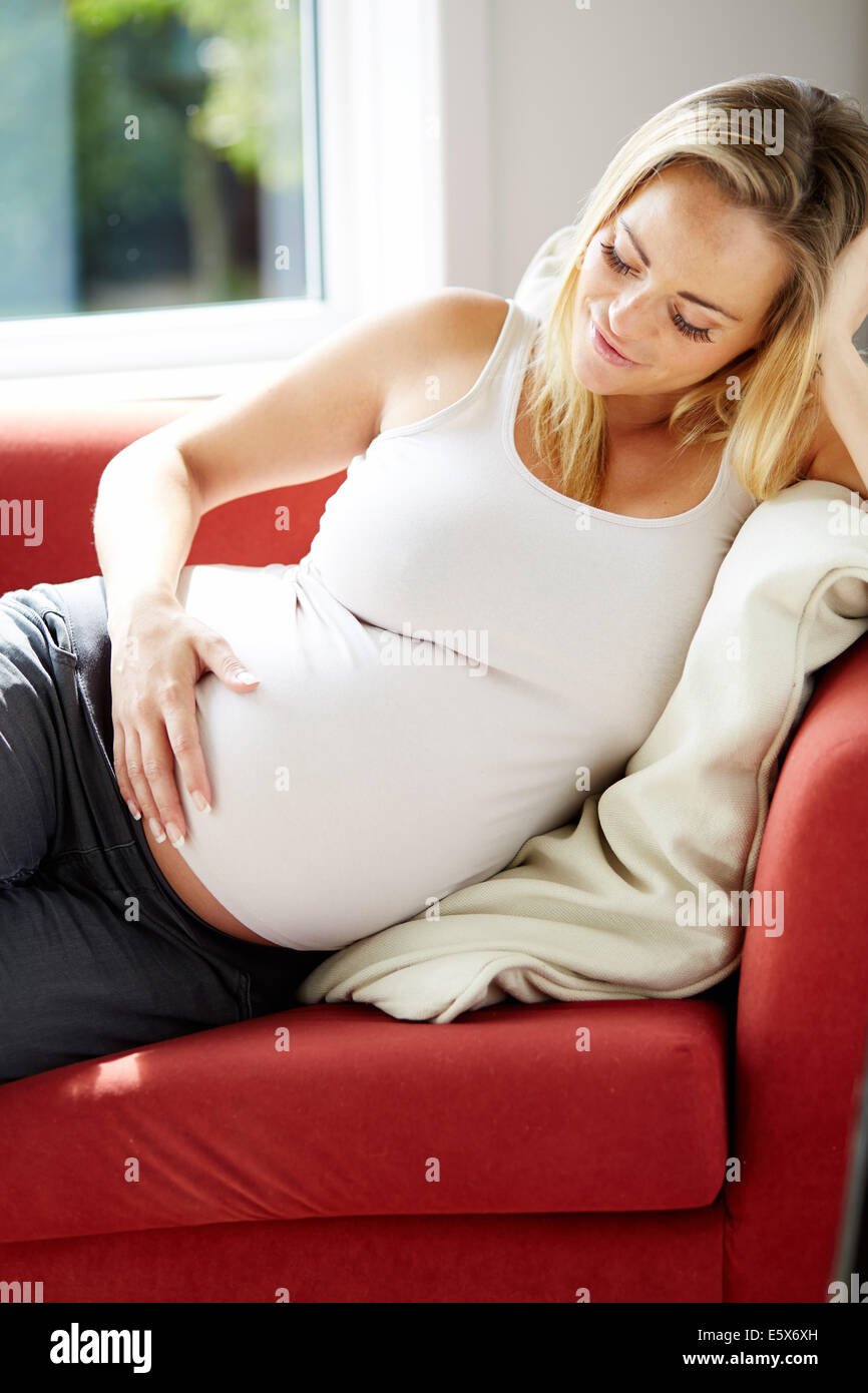 Schwangere Frau saß entspannend auf sofa Stockfoto