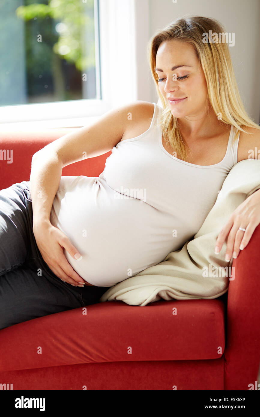 Schwangere Frau saß entspannend auf sofa Stockfoto