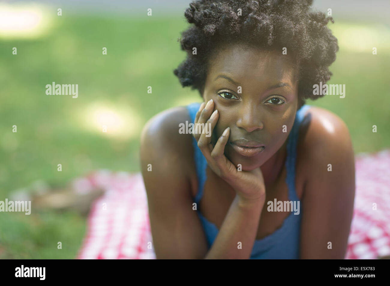 Porträt der jungen Frau liegt auf der Picknickdecke im park Stockfoto