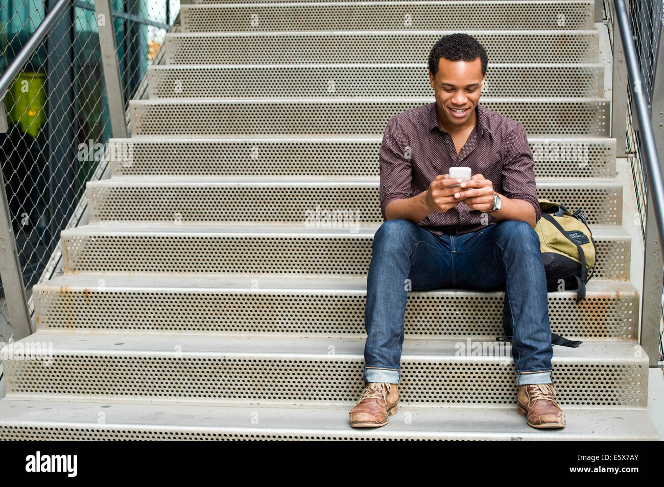 Junger Mann SMS auf Smartphone auf Stadt-Treppe Stockfoto