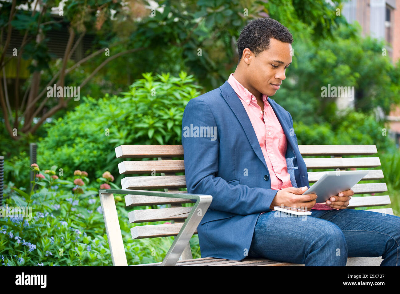 Junger Geschäftsmann sitzt auf der Parkbank Blick auf digital-Tablette Stockfoto