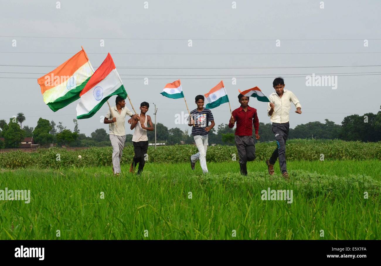 Allahabad, Indien. 7. August 2014. Dorfbewohner Kinder laufen mit dreifarbigen Flagge im Reisfeld Paddy vor Unabhängigkeitstag in Allahabad am 14. August 2014. © Prabhat Kumar Verma/Pacific Press/Alamy Live-Nachrichten Stockfoto