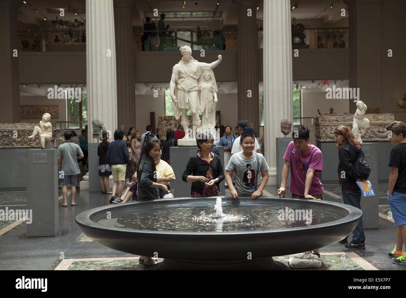 Junge chinesische Touristen machen einen Wunsch in den Brunnen in den griechischen & Roman Galerien im Metropolitan Museum in New York City. Stockfoto