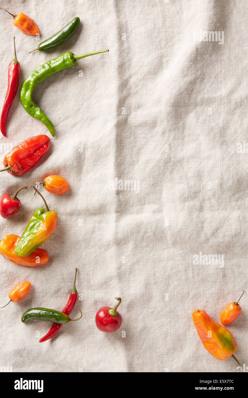Auswahl an Sommer Chili Paprika auf ein Elfenbein Leinen Oberfläche Stockfoto
