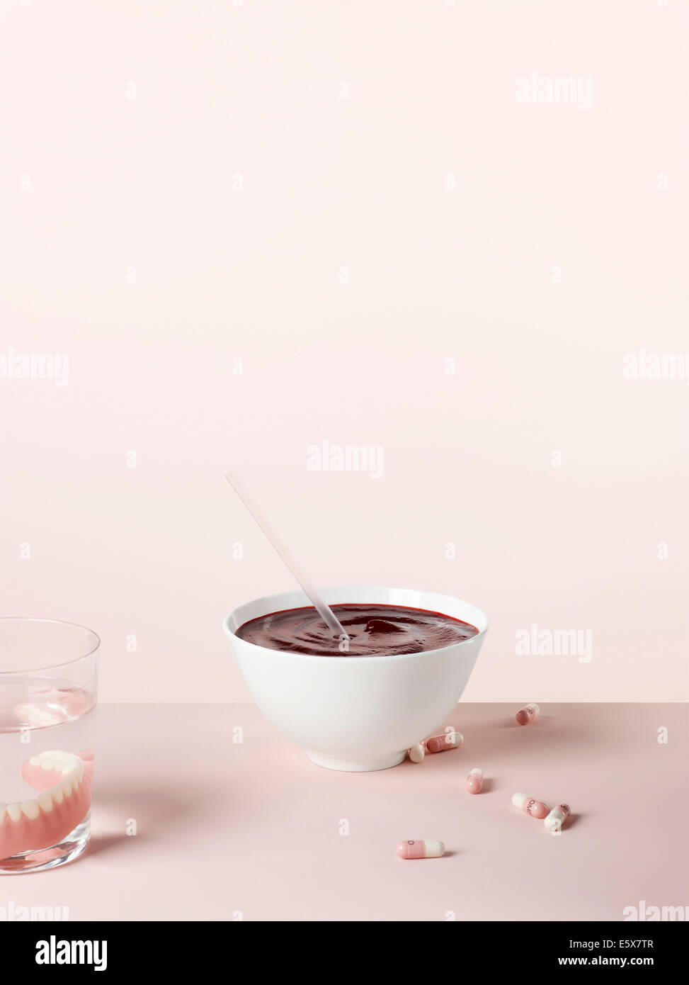 Weiche Speisen für Senioren mit pürierte rote Bete Suppe und trinken Stroh. Pillen und Zahnersatz im Trinkglas Stockfoto