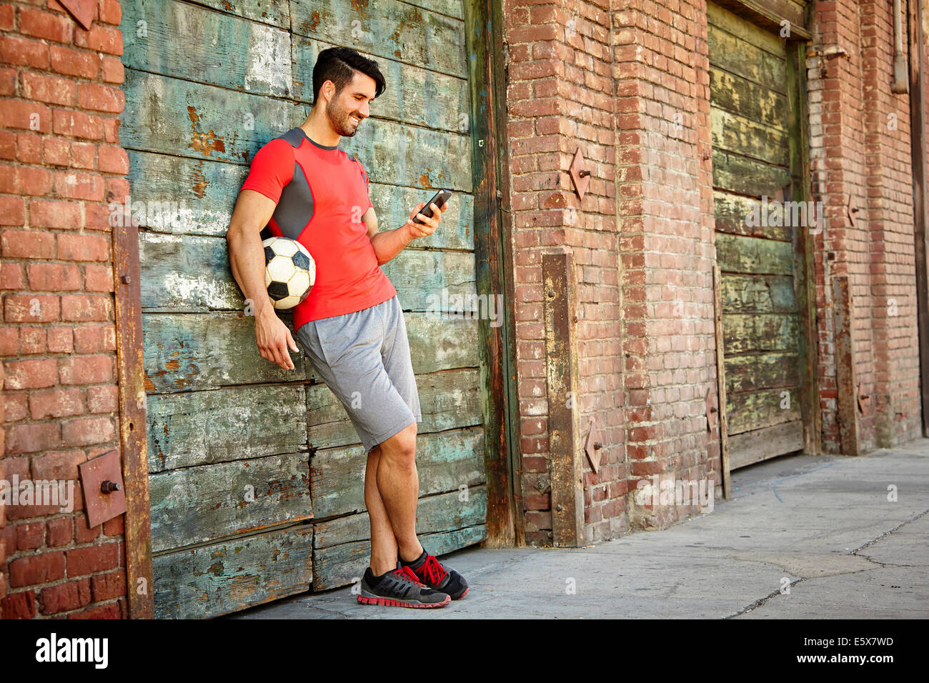 Junge männliche Fußball Spieler SMS auf smartphone Stockfoto