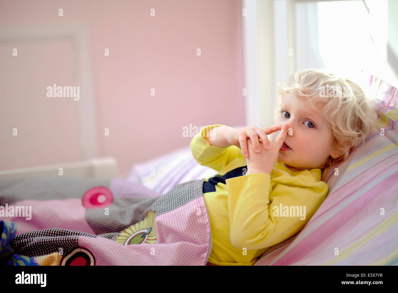 Männliche Kleinkind liegend im Bett machen geheime Geste Handzeichen Stockfoto