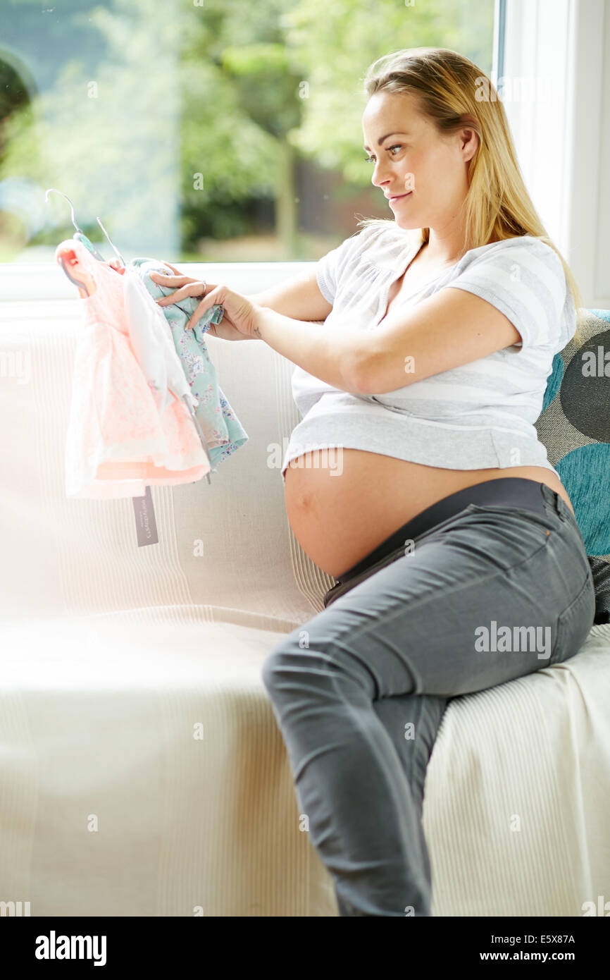 Schwangere Frau betrachten Baby-Kleidung Stockfoto