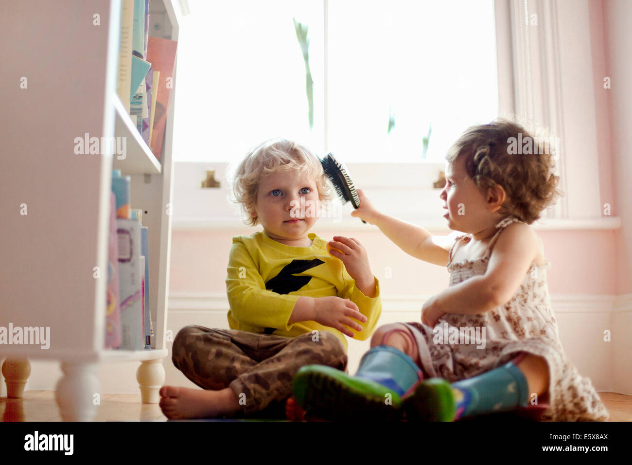 Weiblichen Kleinkind Bürsten männlichen Kleinkindern Haare im Spielzimmer Stockfoto